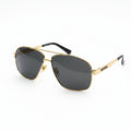A pair of aviator-style sunglasses with a gold metal frame and dark tinted lenses, resting on a white surface.