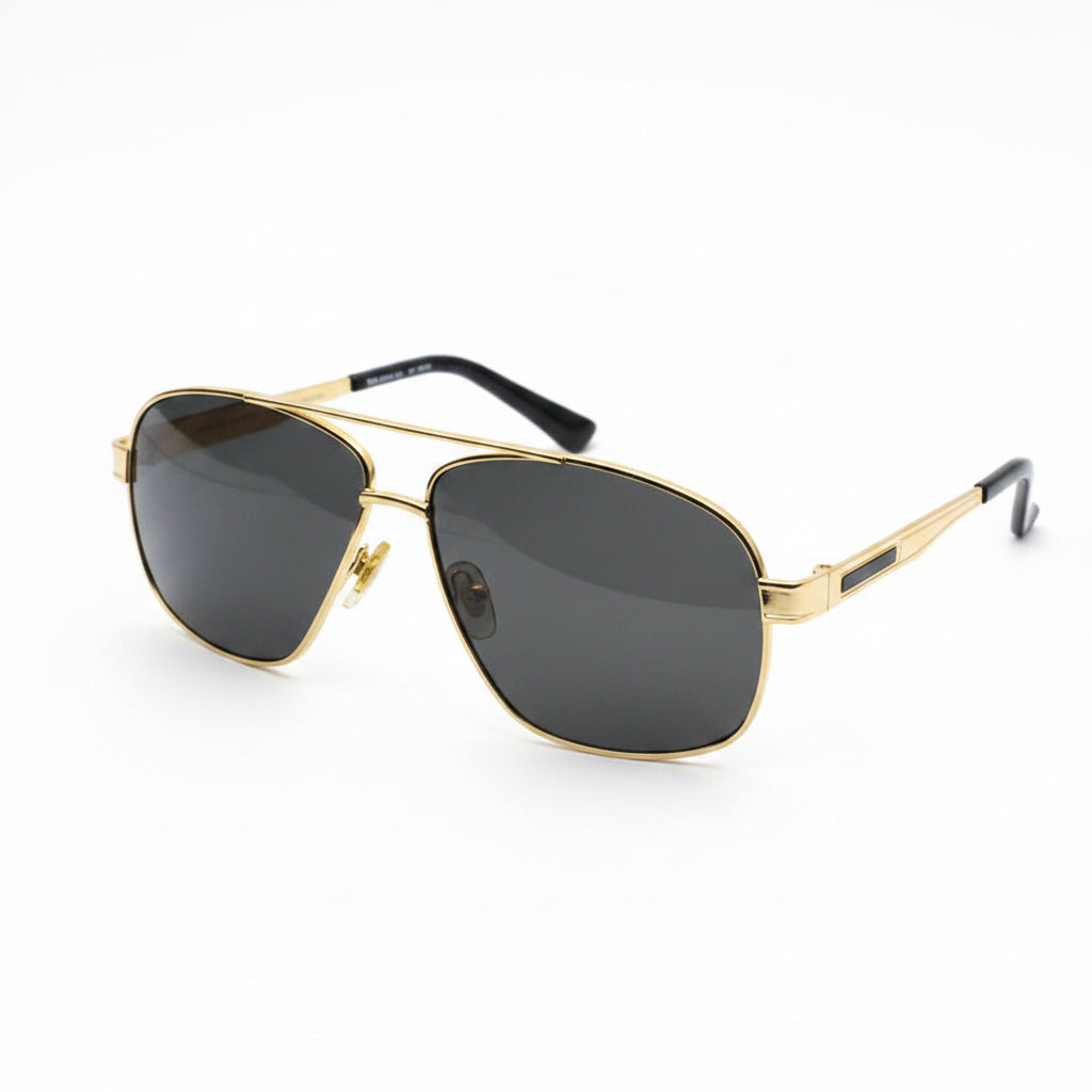 A pair of aviator-style sunglasses with a gold metal frame and dark tinted lenses, resting on a white surface.