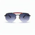 Ray-Ban aviator sunglasses with a black metal frame, gradient gray lenses, and a signature red bridge, displayed on a white surface with softbox lights in the background.
