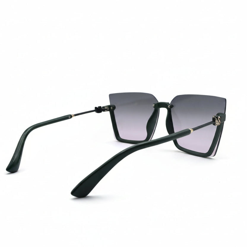 A pair of square-frame sunglasses with a matte black frame and dark gray-to-pink gradient lenses, displayed on a white surface between two silver studio reflector panels.