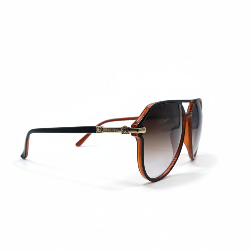 Dior aviator sunglasses with dark brown gradient lenses and gold metal frames, displayed on a white surface between two silver textured panels.