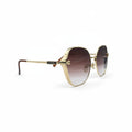 Prada oversized square sunglasses with gold metal frames and brown gradient lenses, displayed on a white surface between two gray fabric light stands.