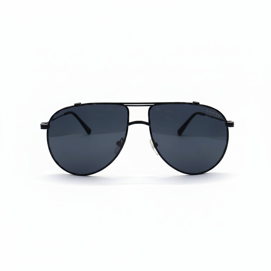 A pair of classic aviator sunglasses with a thin black metal frame and dark gray lenses, displayed on a white surface with two silver studio reflectors in the background.