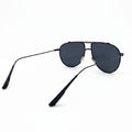 A pair of classic aviator sunglasses with dark gray lenses and a thin black metal frame, displayed on a white surface with a reflective silver backdrop.