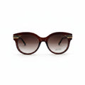 Gucci cat-eye sunglasses with a translucent dark brown frame and gradient brown lenses, featuring gold metal double stripes on the temples and the Gucci logo on the lens.