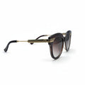 Gucci cat-eye sunglasses with a tortoiseshell acetate frame, gold metal double bridge, and brown gradient lenses, displayed on a white surface between two gray fabric light stands.