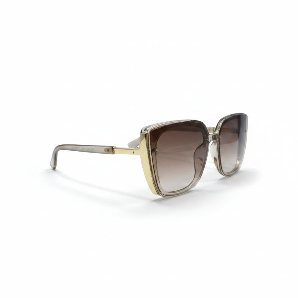 A pair of oversized square sunglasses with a translucent taupe-brown acetate frame and brown gradient lenses, displayed on a white surface with two textured silver props on either side.