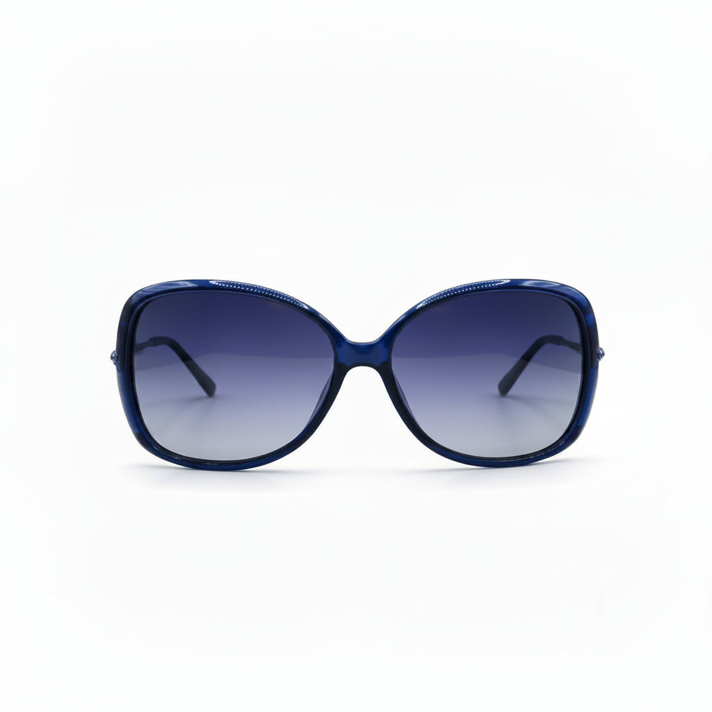 Oversized cat-eye sunglasses with a dark blue acetate frame and gradient purple lenses, displayed on a white surface between two silver studio reflectors.
