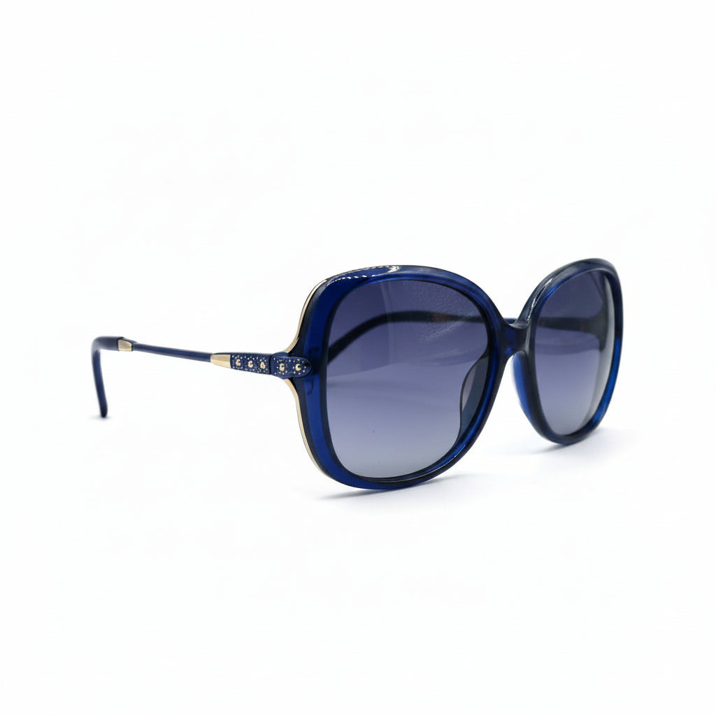 Oversized cat-eye sunglasses with a dark blue acetate frame and gradient purple lenses, displayed on a white surface between two silver studio reflectors.