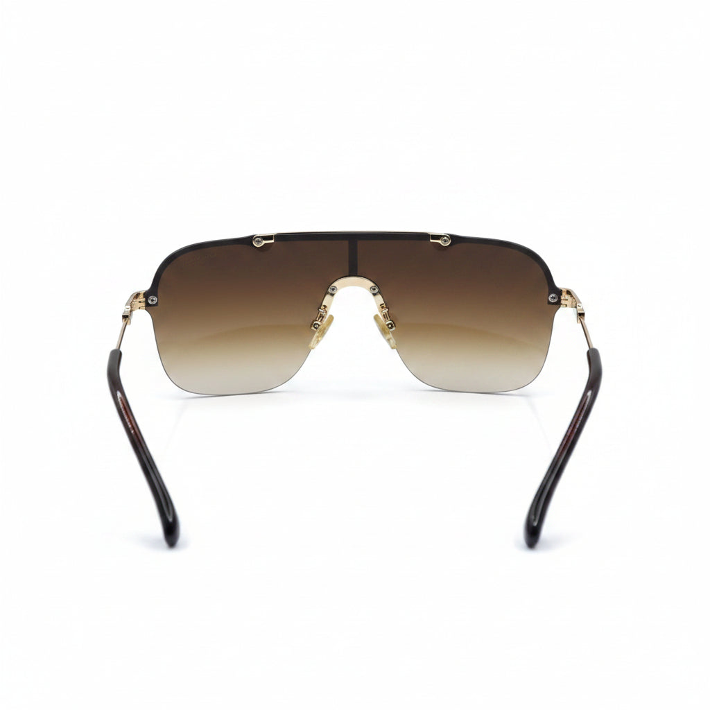 A pair of square shield-style sunglasses with a brown gradient lens, gold metal frame, and tortoiseshell temples, displayed on a white surface with silver studio reflectors in the background.