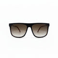 A pair of square-frame sunglasses with a thick black frame and brown gradient lenses, displayed on a white surface with two black fabric panels in the background.