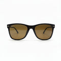 A pair of classic Wayfarer-style sunglasses with a dark brown acetate frame and warm brown-tinted lenses, displayed on a white surface with a reflective silver backdrop.