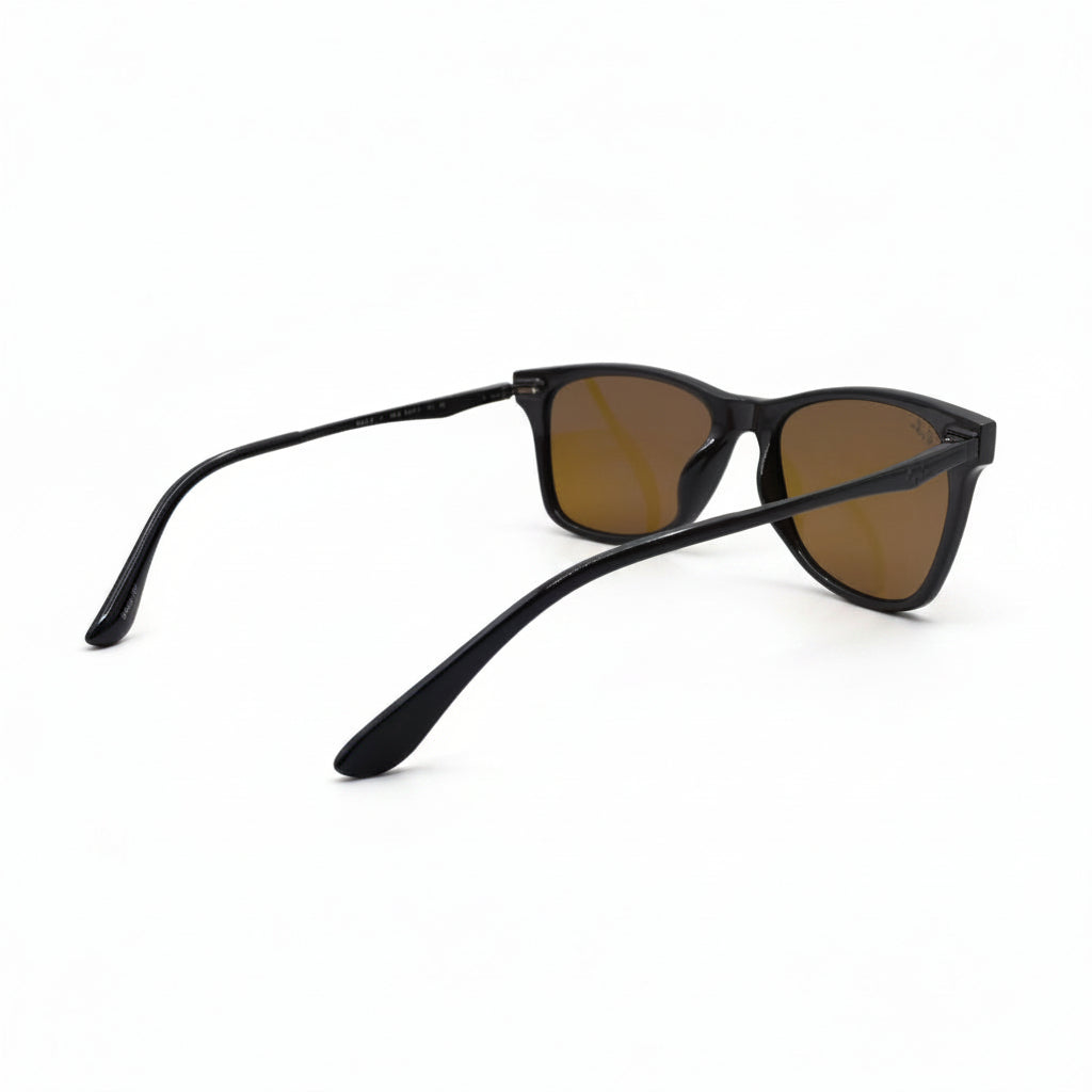 A pair of black acetate sunglasses with brown-tinted lenses, displayed on a white surface with reflective silver paper backing.