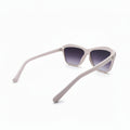 A pair of cat-eye sunglasses with a light pink frame and dark purple tinted lenses, displayed on a white surface with a soft gray background.