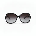 Oversized sunglasses with a chunky black frame and gradient brown-tinted lenses, displayed on a white surface with a reflective silver pouch on each side.