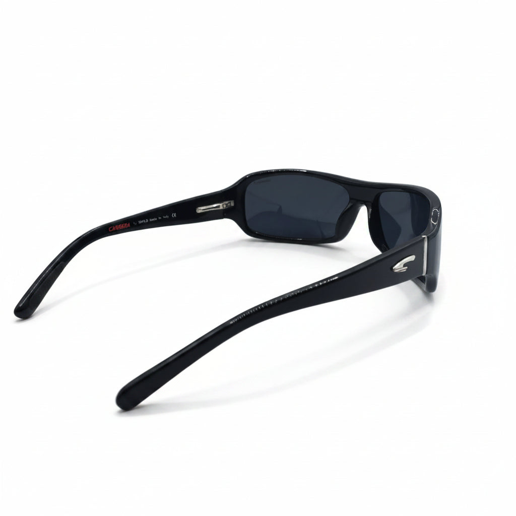 Black rectangular sunglasses with dark lenses and a small silver logo on the temple, displayed on a white surface with reflective silver stands in the background.