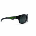 Black Ray-Ban sunglasses with a green accent on the temple arm, displayed on a white surface between two silver reflective stands.