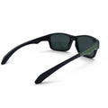 Black wrap-around sunglasses with dark lenses and a green accent on the temple arm, displayed on a white surface between two textured silver panels.