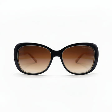 A pair of oversized cat-eye sunglasses with a glossy black frame and brown gradient lenses, displayed on a white surface with a reflective silver backdrop.