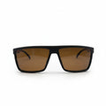 A pair of square-frame sunglasses with a matte black frame and warm brown lenses, displayed on a white surface with two silver studio reflectors in the background.