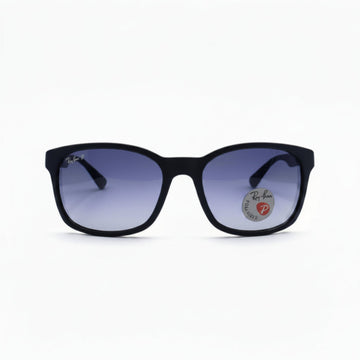 Black square sunglasses with purple gradient lenses, featuring a circular Ray-Ban logo sticker on the right lens, set against a white background with textured black side panels.