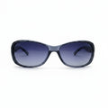 A pair of women's sunglasses with a dark gray translucent frame and gradient purple-blue lenses, displayed on a white surface with two textured gray props on either side.