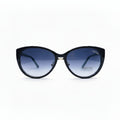 A pair of cat-eye sunglasses with a black frame and blue gradient lenses, displayed on a white surface with textured gray props on either side.