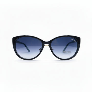 A pair of cat-eye sunglasses with a black frame and blue gradient lenses, displayed on a white surface with textured gray props on either side.