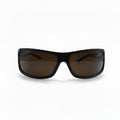 A pair of wrap-around sunglasses with a black frame and brown tinted lenses, displayed on a white surface with two silver reflective stands on either side.