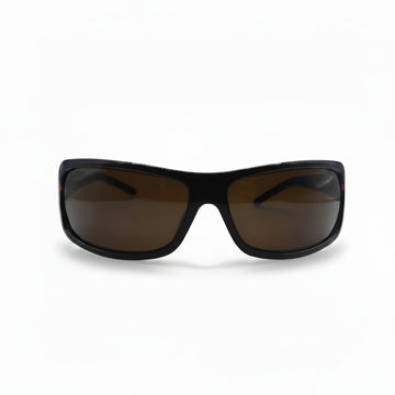 A pair of wrap-around sunglasses with a black frame and brown tinted lenses, displayed on a white surface with two silver reflective stands on either side.