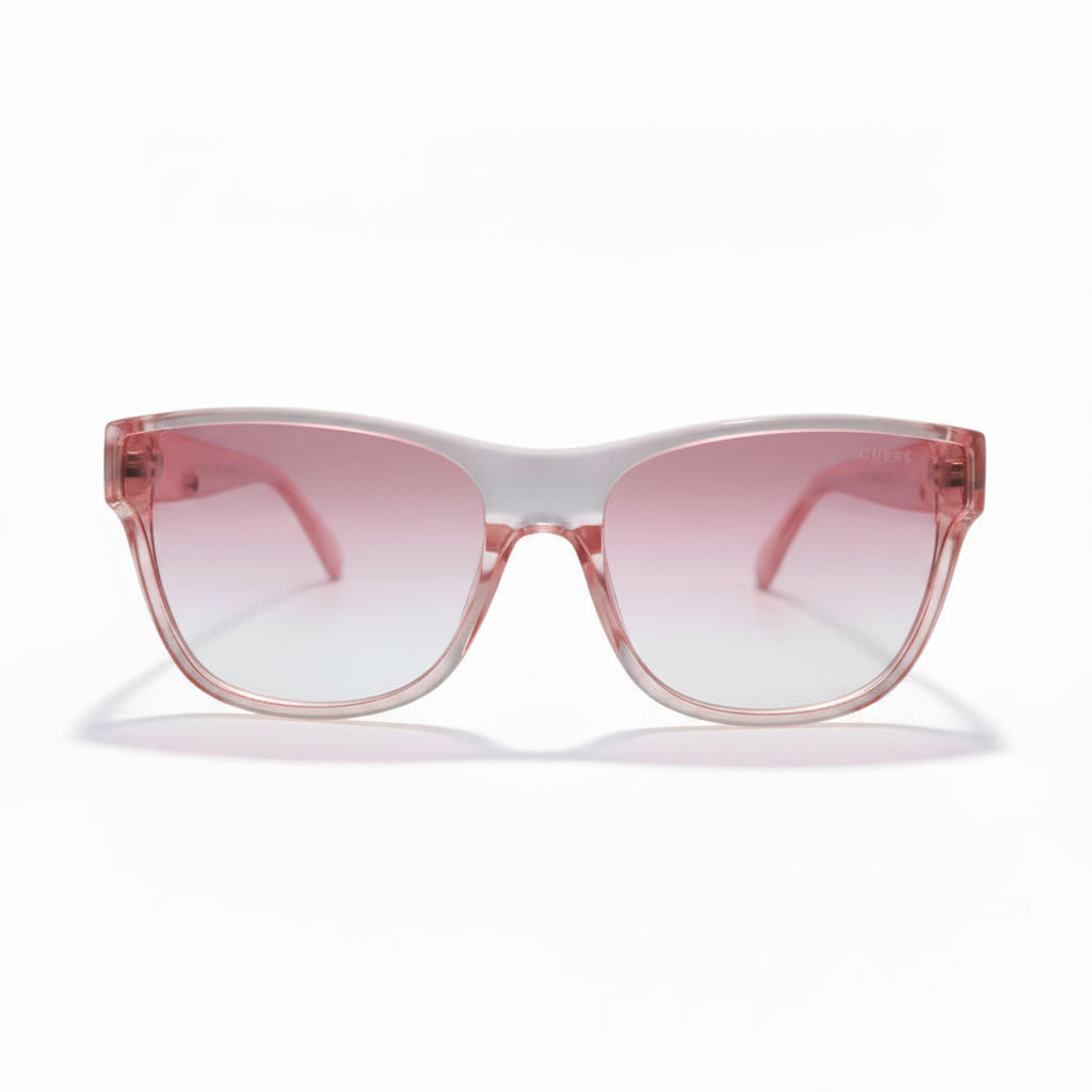 Pink cat-eye sunglasses with a translucent pink frame and pink gradient lenses, displayed on a white surface with black studio lights in the background.