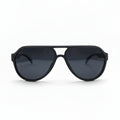 Black aviator-style sunglasses with dark lenses, displayed on a white surface with a reflective silver backdrop visible on both sides.