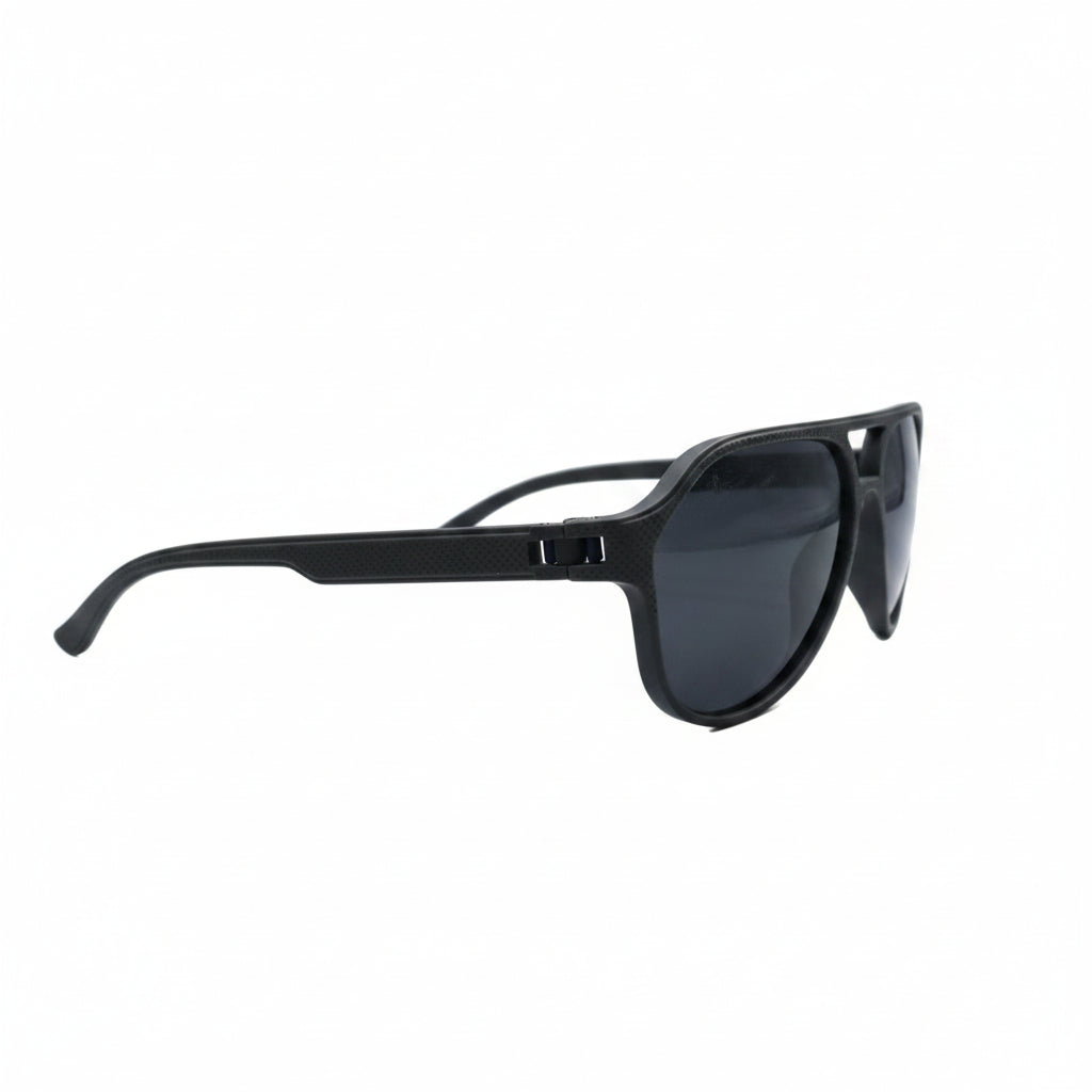 Black aviator-style sunglasses with dark lenses, displayed on a white surface with a reflective silver backdrop visible on both sides.