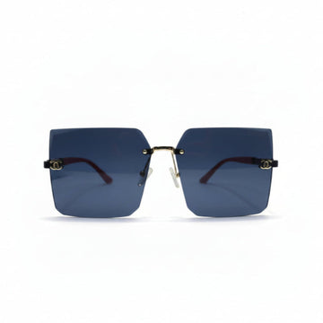 Rimless square sunglasses with dark blue lenses, gold metal frames, and red temple tips, displayed on a white surface with two black textured props on either side.