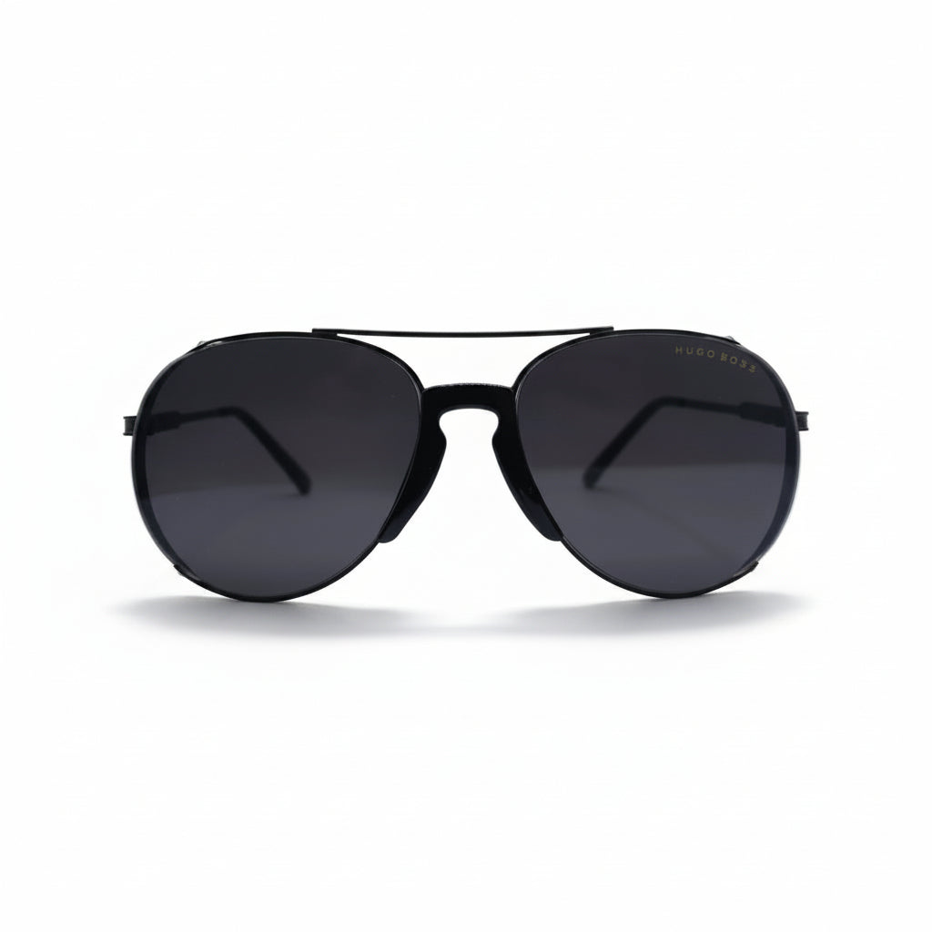 A pair of black aviator sunglasses with dark lenses, displayed on a white surface with a reflective silver backdrop.