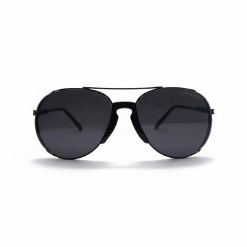 A pair of black aviator sunglasses with dark lenses, displayed on a white surface with a reflective silver backdrop.