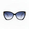 Black cat-eye sunglasses with gradient blue lenses and gold-tone metal accents, displayed on a white surface with a soft shadow.