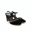 A pair of black pointed-toe high heels with ankle straps and a row of gold rhinestone embellishments across the toes, shown on a white studio background.