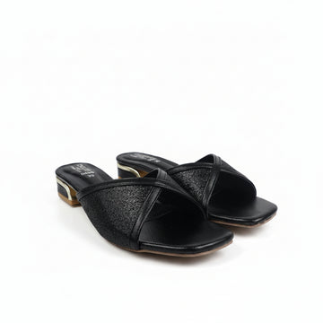 A pair of black leather slide sandals with textured glittery straps and low block heels with gold-toned detailing, photographed on a white fabric background.