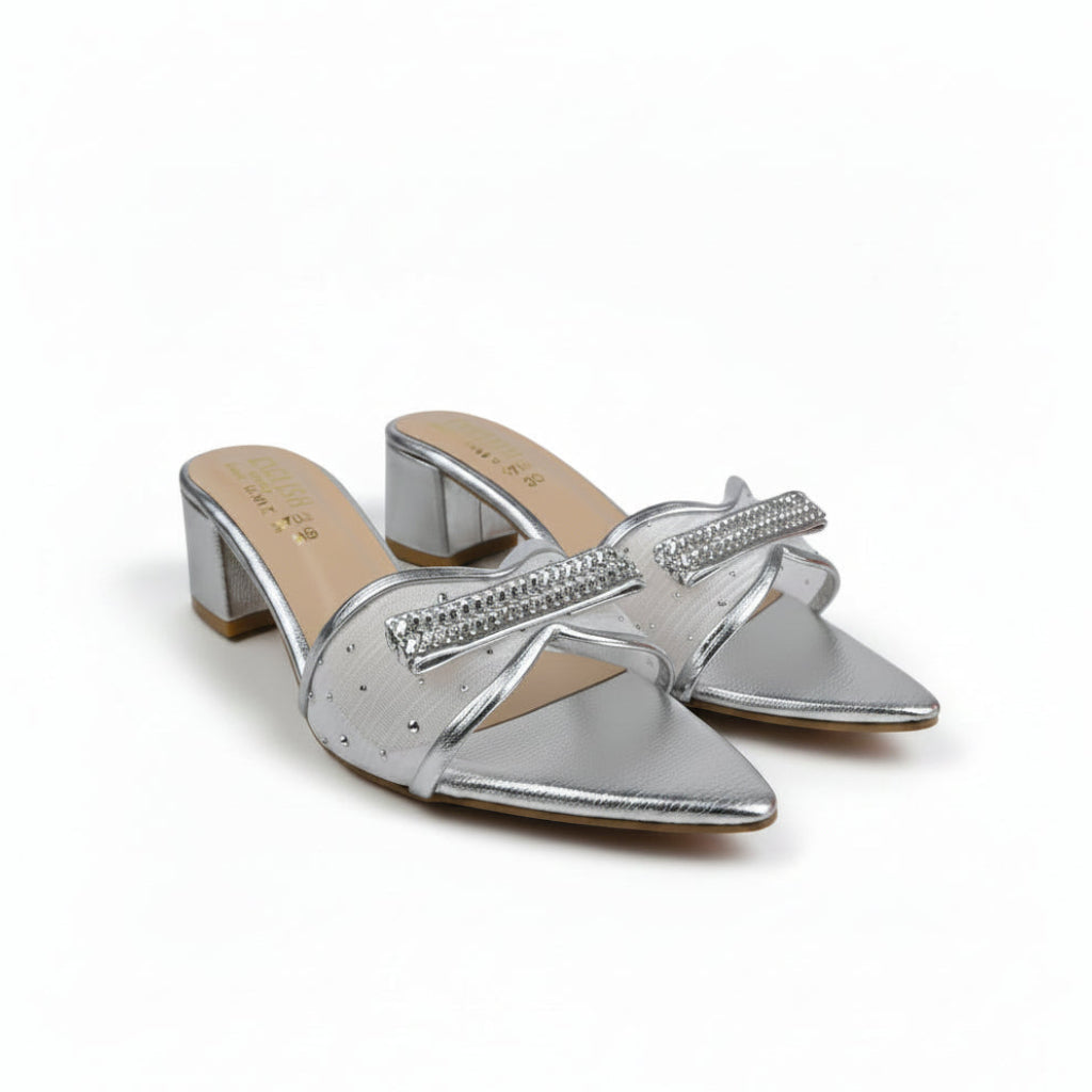 A pair of metallic silver pointed-toe mule sandals with rhinestone-embellished straps and block heels, shown on a light gray surface with a red box partially visible at the right edge.