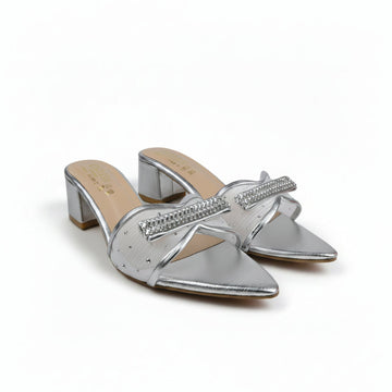 A pair of metallic silver pointed-toe mule sandals with rhinestone-embellished straps and block heels, shown on a light gray surface with a red box partially visible at the right edge.