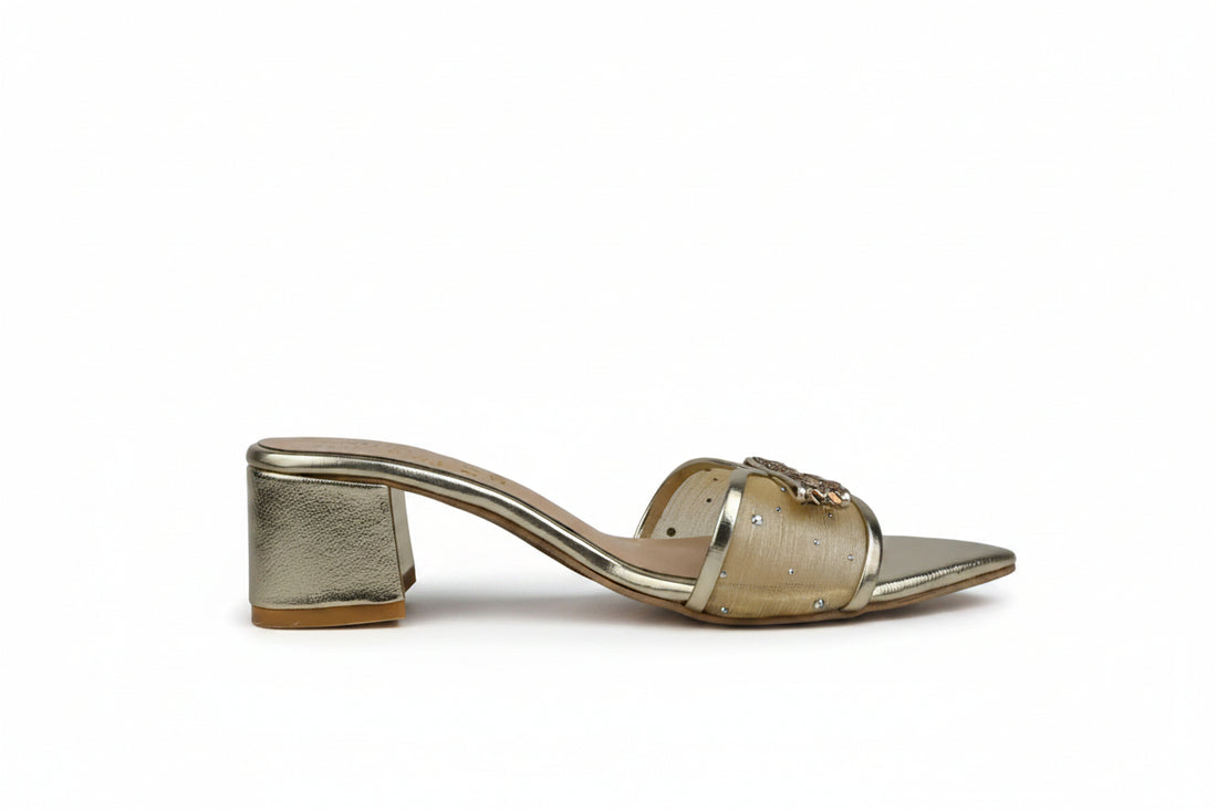 A pair of metallic silver pointed-toe mule sandals with rhinestone-embellished straps and block heels, shown on a light gray surface with a red box partially visible at the right edge.