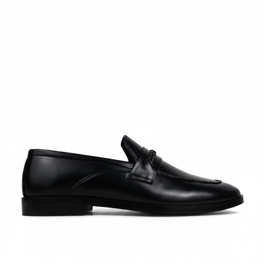 A single black leather penny loafer shown in profile against a light gray fabric backdrop.