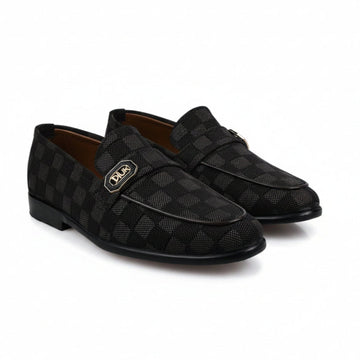 A pair of black checkered loafers with a gold-tone metal logo plaque on the side, displayed on a white fabric background.