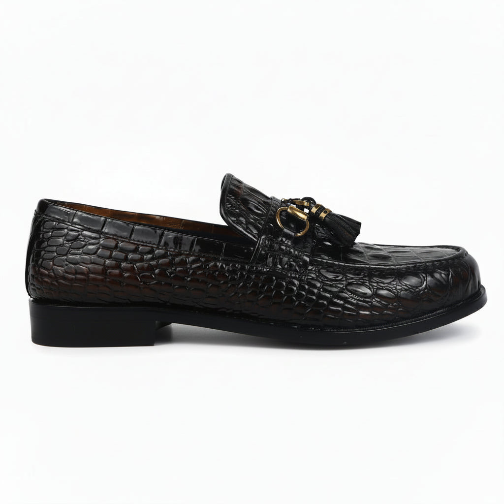 A pair of dark brown crocodile-embossed leather loafers with gold-tone horsebit details and tassel straps, displayed on a white studio background.
