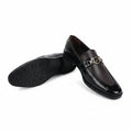 A pair of men's black leather loafers with a gold-tone metal horsebit detail across the vamp, shown on a white studio background. One shoe is standing upright while the other lies on its side to display the black rubber sole.