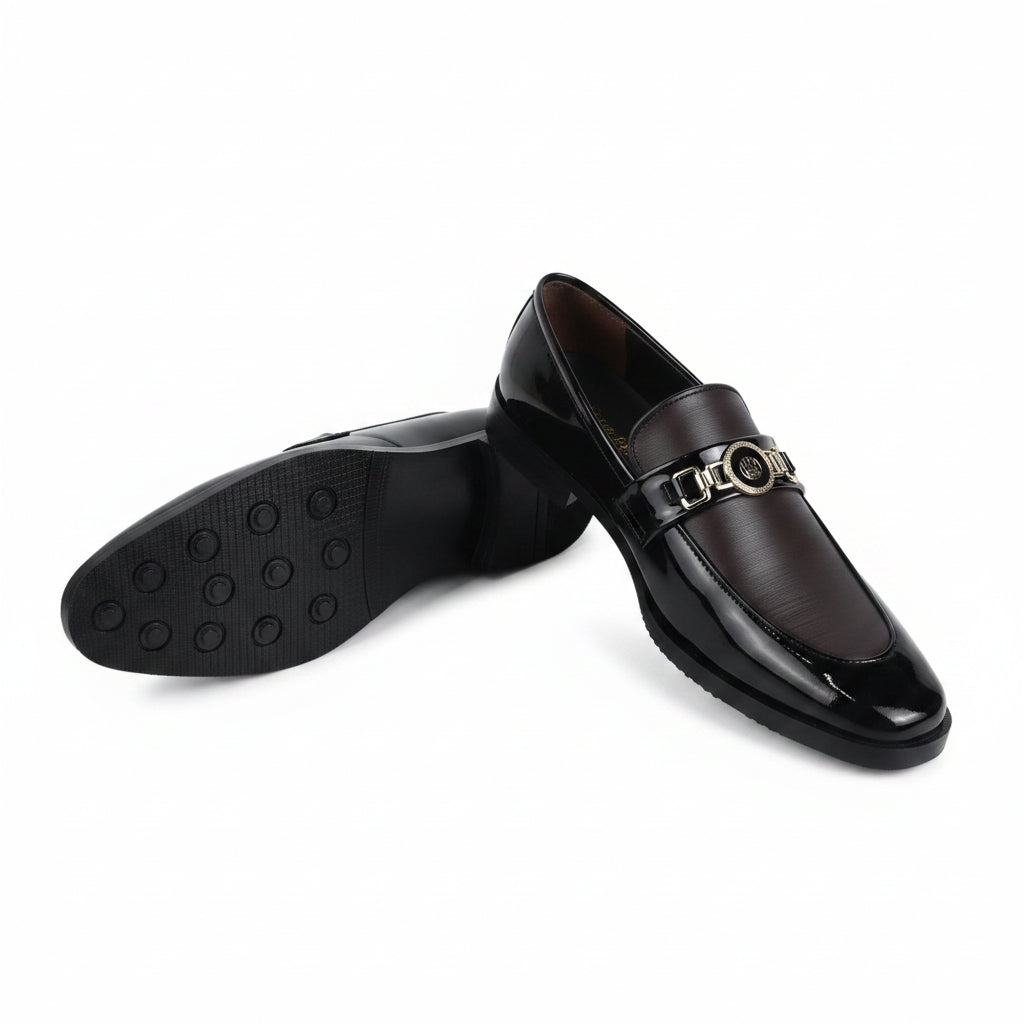 A pair of men's black leather loafers with a gold-tone metal horsebit detail across the vamp, shown on a white studio background. One shoe is standing upright while the other lies on its side to display the black rubber sole.