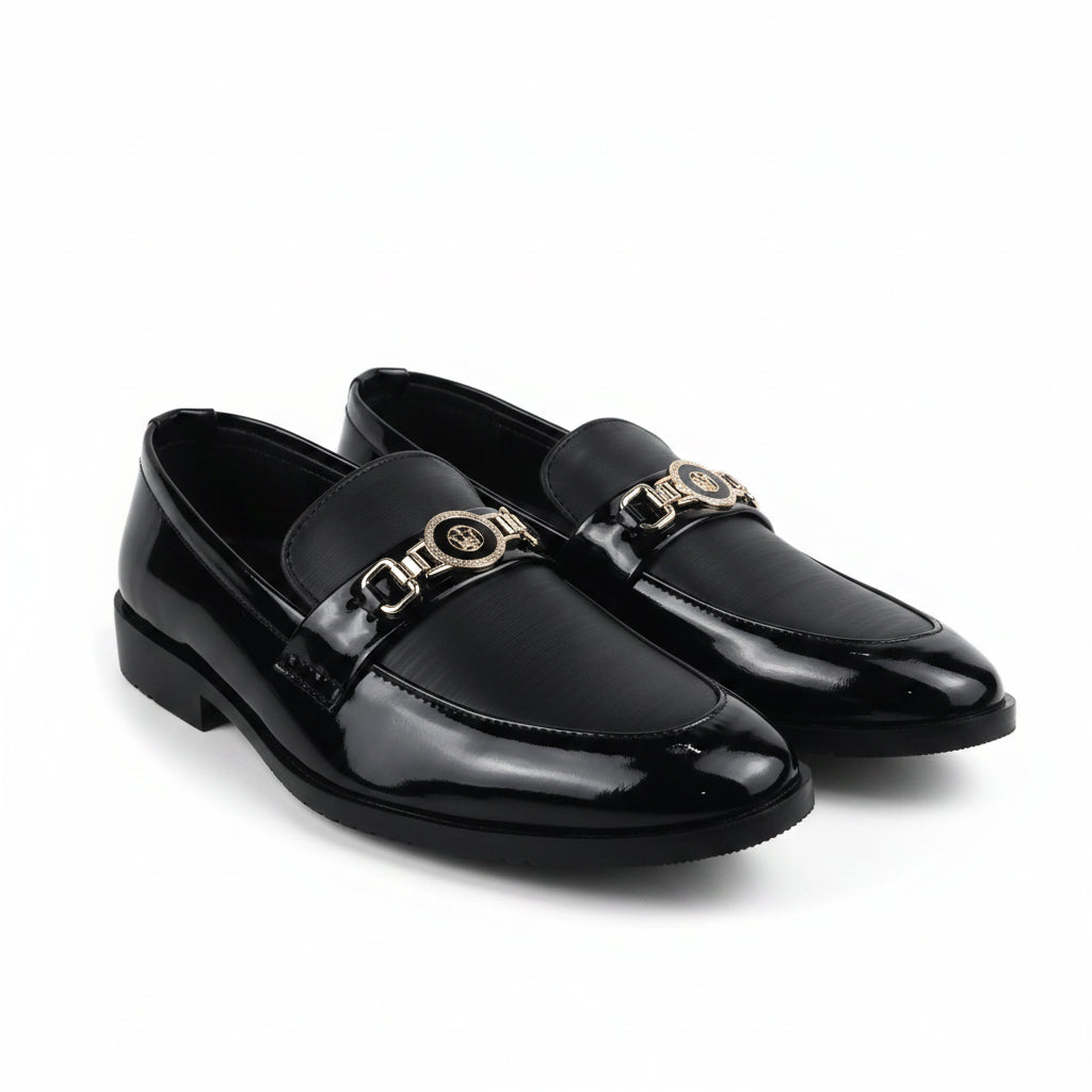 A pair of black leather penny loafers with a prominent gold-tone chain link detail across the vamp, displayed on a white studio background.