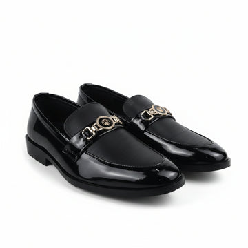 A pair of black leather penny loafers with a prominent gold-tone chain link detail across the vamp, displayed on a white studio background.