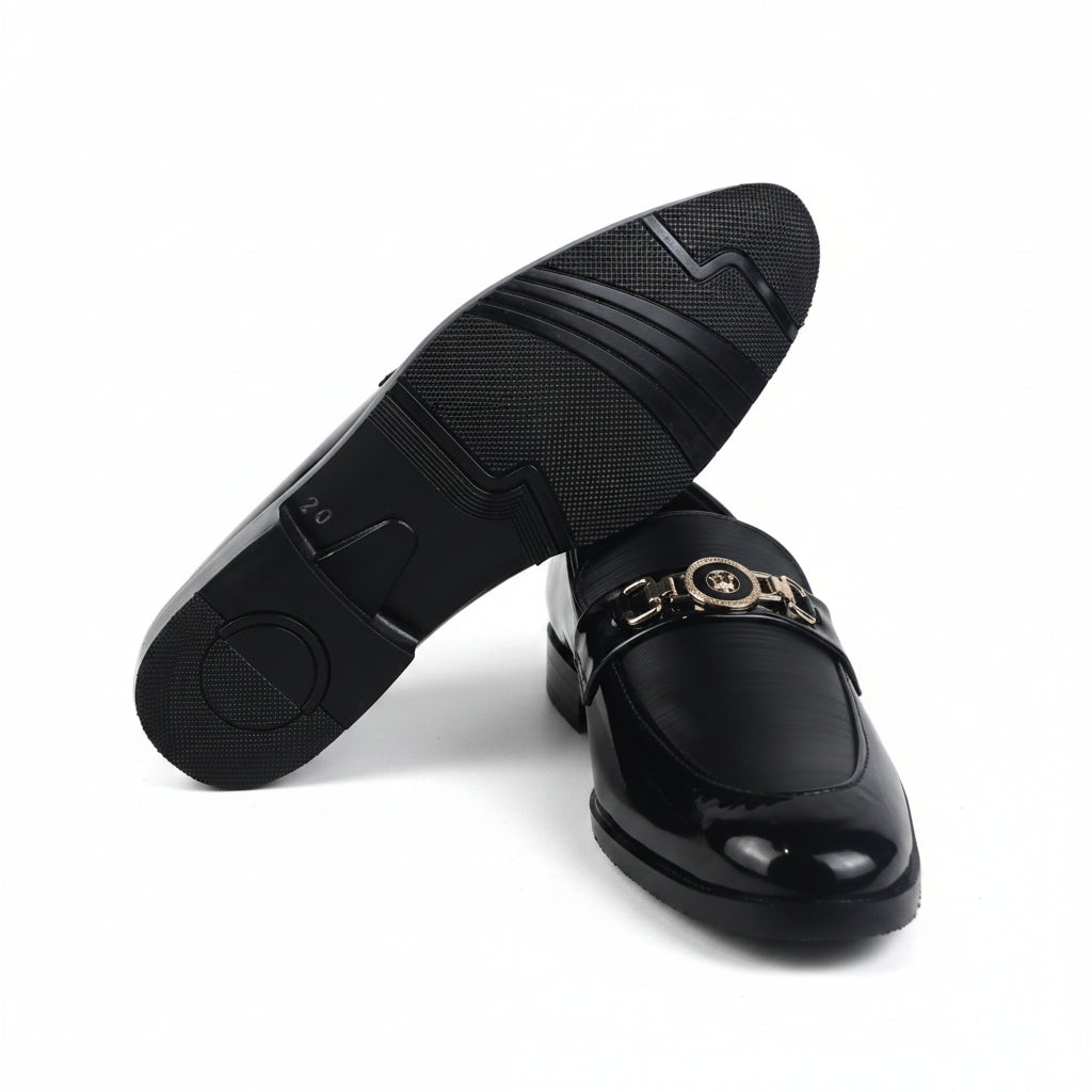 A pair of black leather penny loafers with a gold-tone double-G buckle detail, shown on a white studio background with one shoe turned to display the sole.